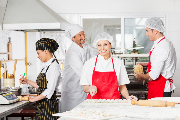 Confident Chef Cutting Ravioli Pasta With Colleagues In Backgrou - Foto, Bild