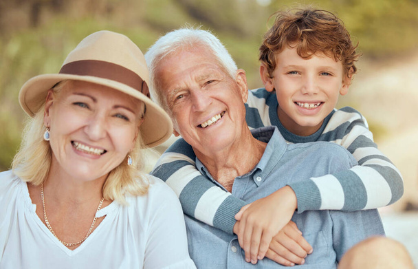 Glückliche kaukasische Großeltern, die mit ihrem Enkel am Strand sitzen. Liebenswert, fröhlich, kindliche Bindung zu Großmutter und Großvater in einem Garten oder Park draußen. Junge bei Pflegeeltern. - Foto, Bild