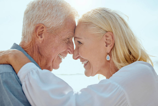 A happy mature caucasian couple enjoying fresh air on vacation at the beach. Smiling retired couple hugging and embracing while bonding outside together. - Fotoğraf, Görsel