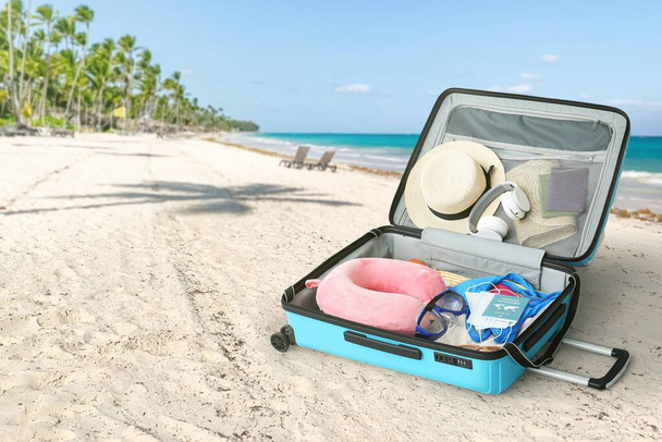 Open suitcase on beach sand. Travel concept - Foto, afbeelding