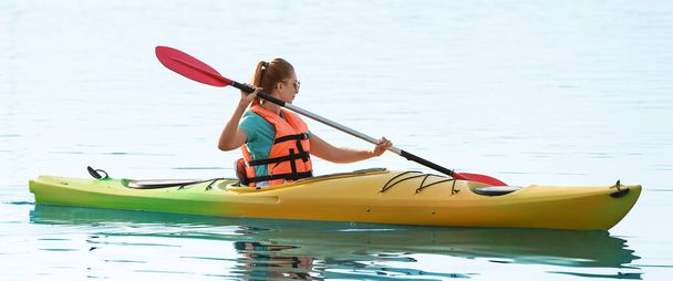 Young woman kayaking in river on summer day - Valokuva, kuva