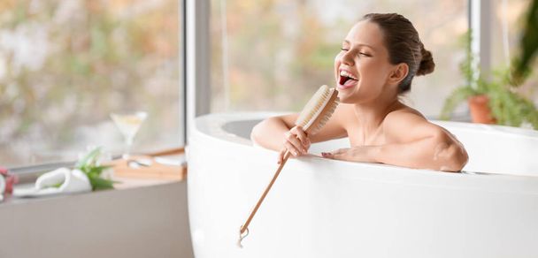 Όμορφη νεαρή γυναίκα τραγουδά ενώ κάνει μπάνιο στο σπίτι - Φωτογραφία, εικόνα