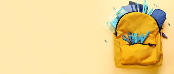 School backpack and stationery on yellow background with space for text - 写真・画像