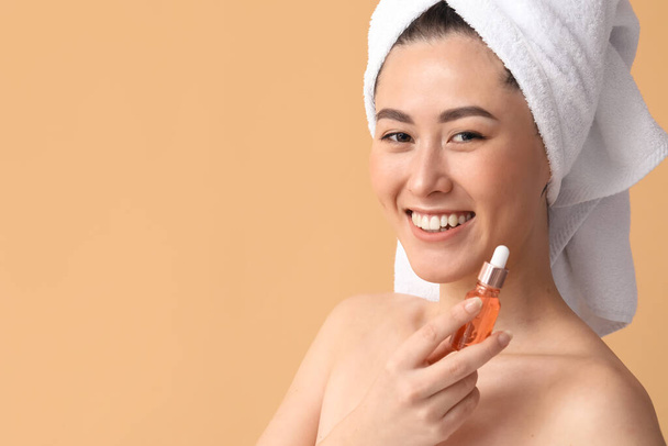 Giovane donna asiatica con siero cosmetico su sfondo beige - Foto, immagini
