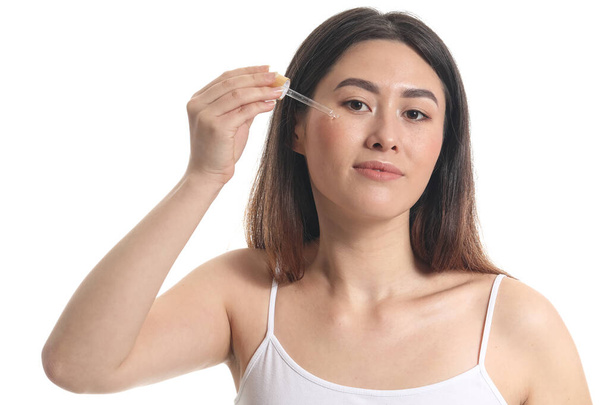 Mujer asiática joven con suero cosmético aislado en blanco - Foto, imagen