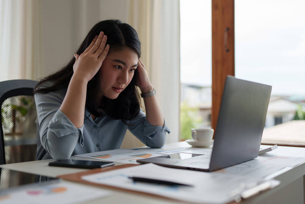 Image of Asian Business woman stressed while analyzing financial report balance. Financial and investment concept - Fotó, kép