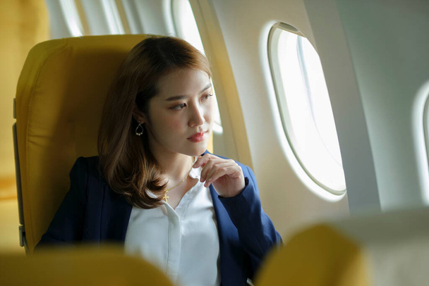 Молодая деловая женщина в самолете посмотреть в окно самолета, концепция путешествия. - Фото, изображение
