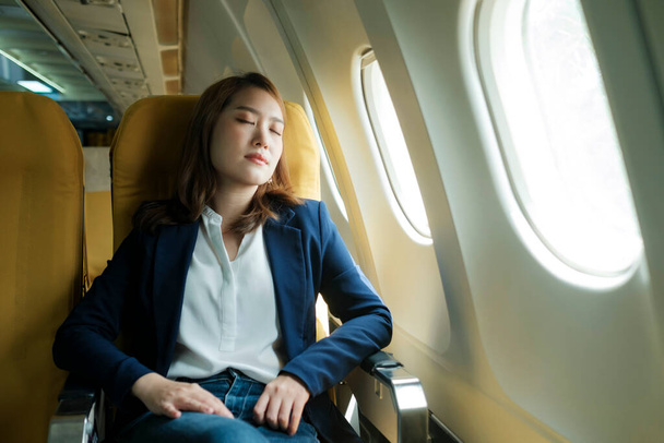 Młoda bizneswoman W samolocie śpiąca w samolocie w podróży, koncepcja podróży. - Zdjęcie, obraz