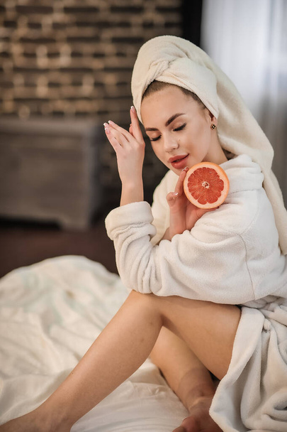 beautiful young woman with a towel on her face and holding a pillow on the bed - Foto, Bild