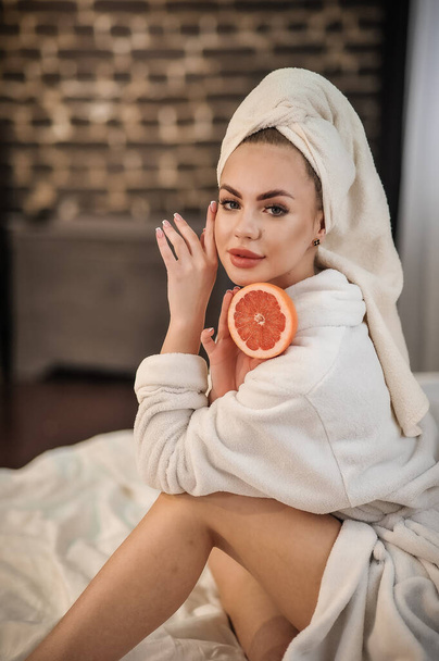 beautiful young woman with a mask on her face and holding a towel on the bed - Photo, image