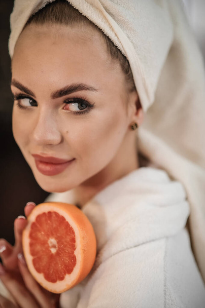 beautiful young woman with a healthy fresh fruit and a towel on her head - Fotó, kép