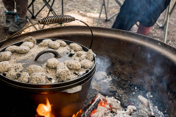 Dutch oven camp cooking with coal briquettes beads on top. Campfire in a firepit. Camping lifestyle - Φωτογραφία, εικόνα