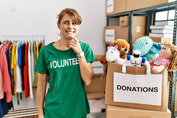 Beautiful caucasian woman wearing volunteer t shirt at donations stand thinking worried about a question, concerned and nervous with hand on chin  - Photo, Image