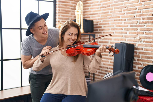 Man and woman musicians playing violin at music studio - Foto, imagen