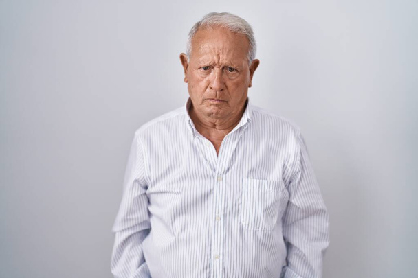 Senior man with grey hair standing over isolated background skeptic and nervous, frowning upset because of problem. negative person.  - Photo, Image
