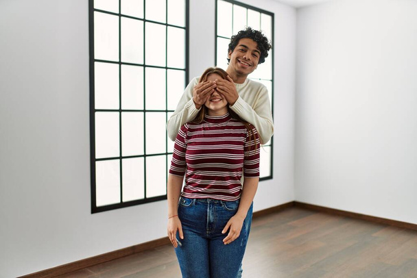 Hombre sorprendiendo a su novia cerrando los ojos con las manos en un nuevo hogar vacío. - Foto, imagen