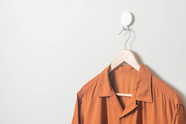 hanging shirt with wood hanger on wall - Φωτογραφία, εικόνα