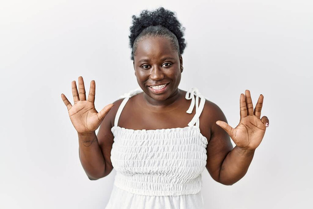 Young african woman standing over white isolated background showing and pointing up with fingers number nine while smiling confident and happy.  - Photo, image