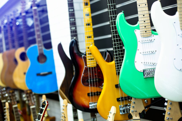 Селективное внимание к электрогитаре с размытыми гитарами висит в музыкальном салоне в магазине музыкальных инструментов - Фото, изображение