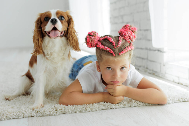 Happy child girl with a dog. The child and the dog are having fun playing at home. High quality photo - Fotó, kép