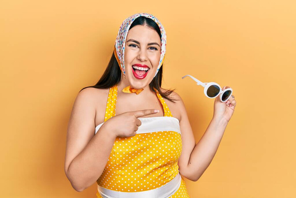 Giovane donna ispanica che indossa pin up stile sorridente felice indicando con mano e dito  - Foto, immagini