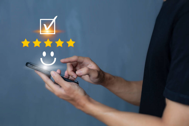 Satisfaction and customer service survey concept, business people using  smartphone. to answer the questionnaire And the satisfaction rating, the satisfaction rating with the smiley face icon 5 stars. - Fotografie, Obrázek