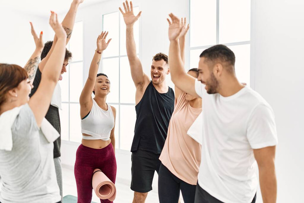 Grupo de jóvenes deportistas sonriendo felices con las manos levantadas en el centro deportivo. - Foto, imagen