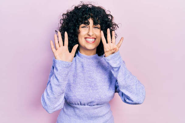 Молодая женщина с Ближнего Востока в повседневной одежде показывает и показывает пальцами номер девять, улыбаясь уверенно и счастливо.  - Фото, изображение