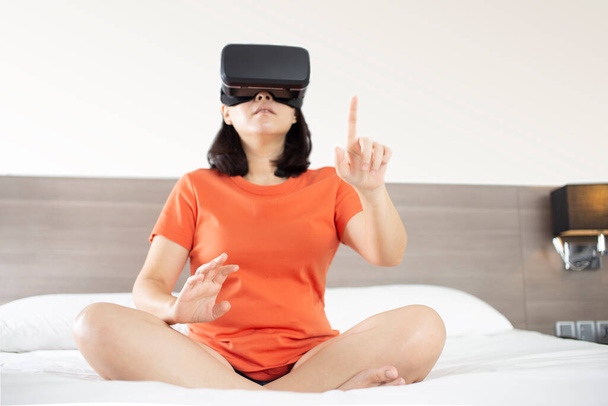 Metaverse technológia fogalmak. Fiatal nők visel virtuális valóság szemüveg modern belsőépítészeti érintse virtuális képernyő fáklyák hatása, homályos háttér - Fotó, kép