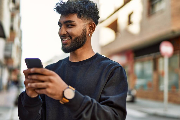 Young arab man smiling confident using smartphone at street - Φωτογραφία, εικόνα