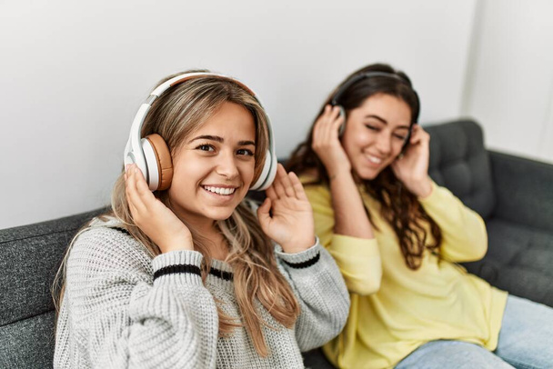 Young couple smiling happy listening to music sitting on the sofa at home. - Photo, Image