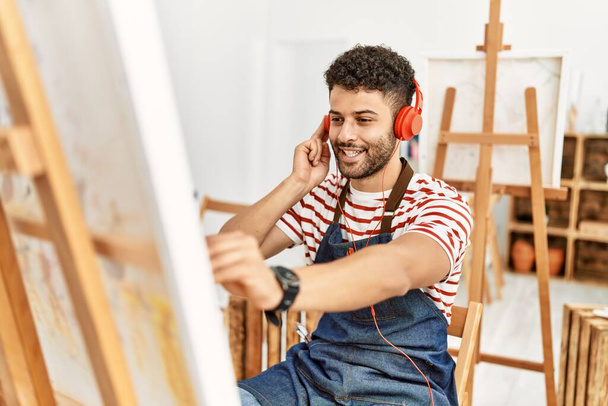 Jovem artista árabe homem ouvindo música desenho no estúdio de arte. - Foto, Imagem
