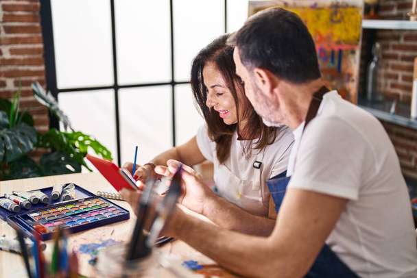 Middle age man and woman artists drawing on notebook using touchpad at art studio - Foto, afbeelding