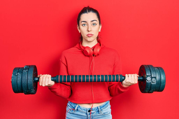 Beautiful woman with blue eyes wearing sportswear using dumbbells depressed and worry for distress, crying angry and afraid. sad expression.  - Foto, Imagen