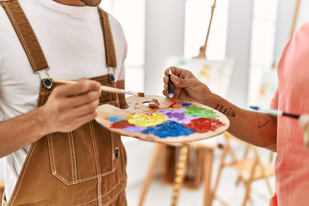 Dois homens hispânicos misturam cores na paleta no estúdio de arte - Foto, Imagem