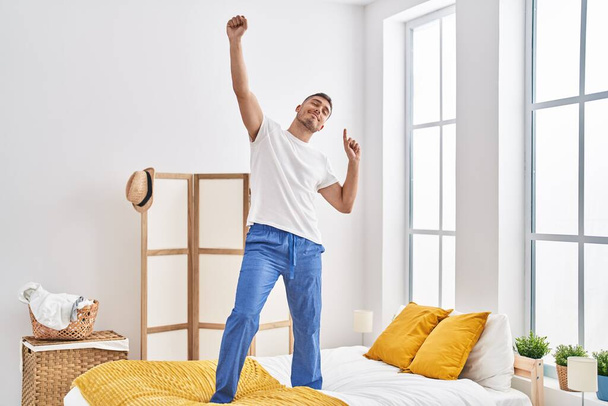 Joven hispano bailando en la cama en el dormitorio - Foto, Imagen