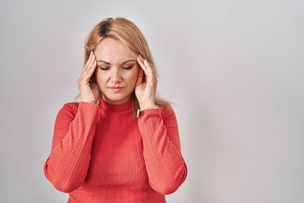 Blonde woman standing over isolated background with hand on head, headache because stress. suffering migraine.  - Foto, Imagen