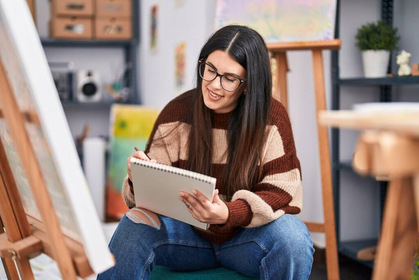 Молода іспаномовна жінка художник малює на ноутбуці в художній студії
 - Фото, зображення