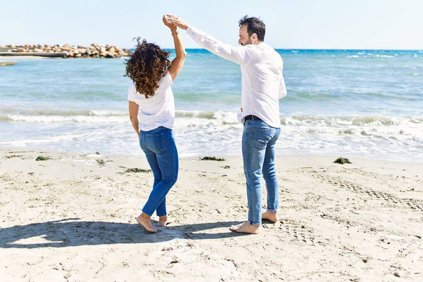 Spanisches Paar mittleren Alters lächelt glücklich tanzend am Strand. - Foto, Bild