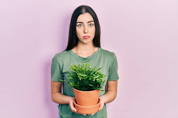 Beautiful woman with blue eyes holding green plant pot depressed and worry for distress, crying angry and afraid. sad expression.  - Foto, Imagem
