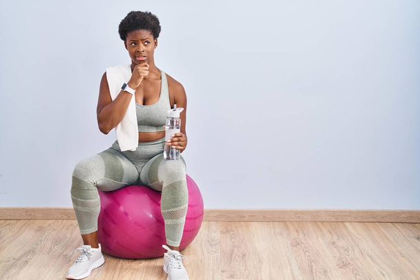 African american woman wearing sportswear sitting on pilates ball thinking worried about a question, concerned and nervous with hand on chin  - Fotografie, Obrázek