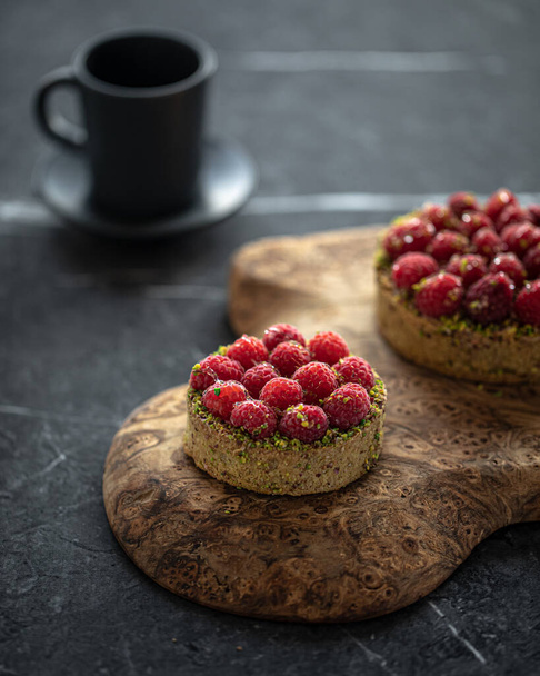 Raspberry tartlets with pistachios and coffee on serving board - Zdjęcie, obraz