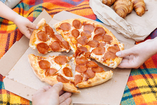 Hands take slices of pepperoni pizza, food delivery, picnic. - Foto, Imagem