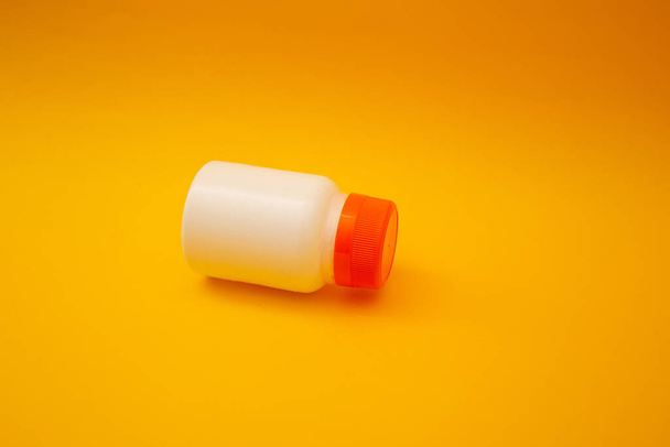 Jar with pills on a yellow background - Fotó, kép