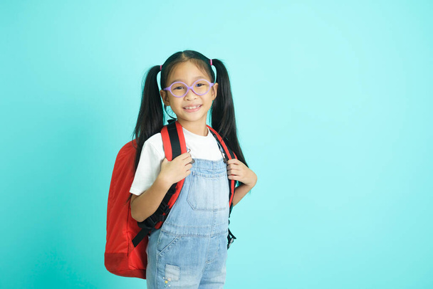 Kid students girl going to school, i like school. Smiling pose for camera on sky blue studio background. school concept. - Foto, imagen