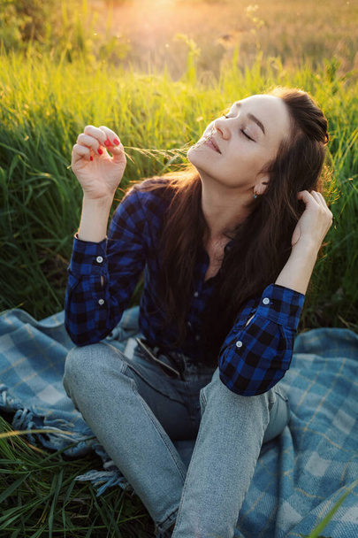 Portrait of a beautiful young woman on meadow watching the sunset enjoying nature summer evening outdoors. - Fotó, kép