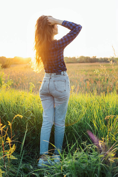 Portrait of a beautiful young woman on meadow watching the sunset enjoying nature summer evening outdoors. - 写真・画像