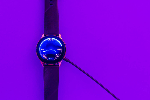 Smart watch on wireless charging with on-screen.Purple,veri peri neon,glowing trendy color background.Top view.Copy space. - Foto, Imagem