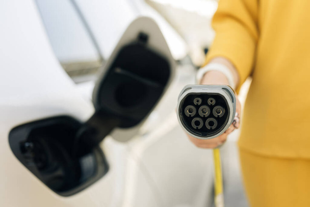 Type 2 CCS plug port cable on electric vehicle. Fast charging socket type 2 combo electric car. DC - CCS type 2 EV charging connector at EV car. Eco friendly alternative energy green environment - Fotó, kép