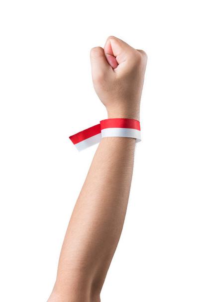Human hand showing ribbon with the red and white color of the Indonesian flag isolated over white background - Foto, afbeelding